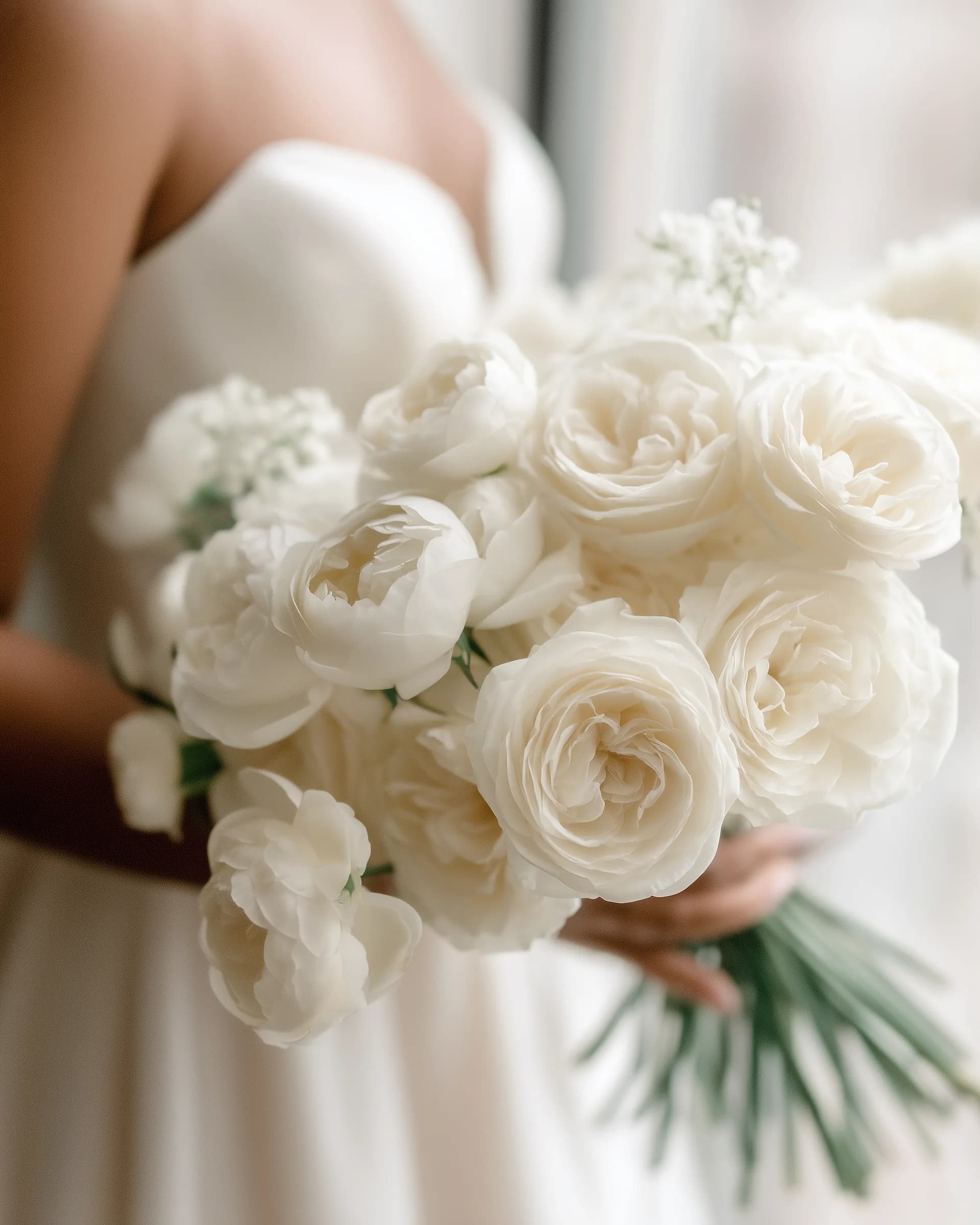Bride holding a white garden rose bouquet, showcasing a florist’s work